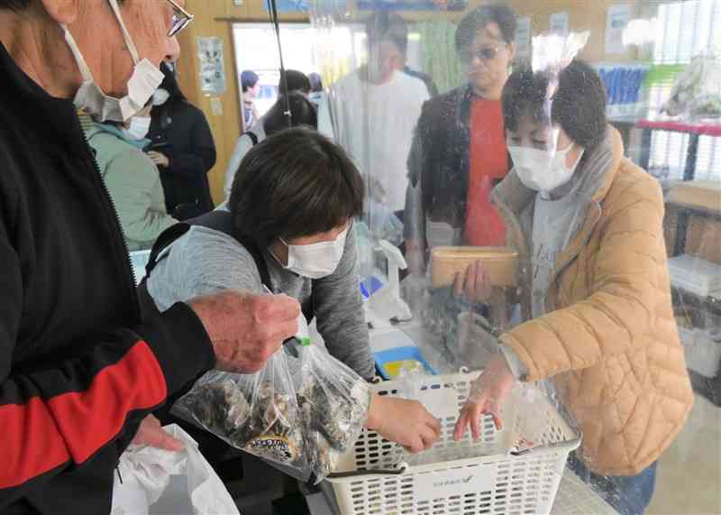 試験販売が始まったカキを買い求める消費者（右）＝18日