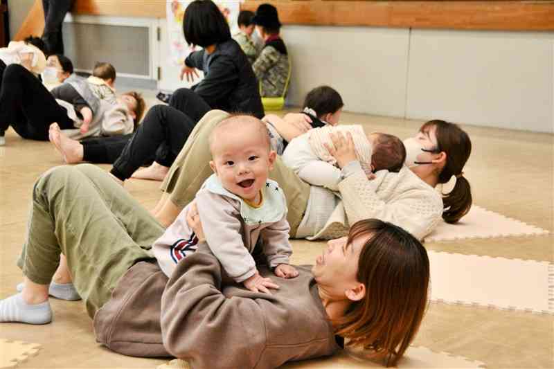 東区の子育てサークルの合同イベントで、体操を楽しんで笑顔を見せる母親と赤ちゃん＝18日、熊本市東区