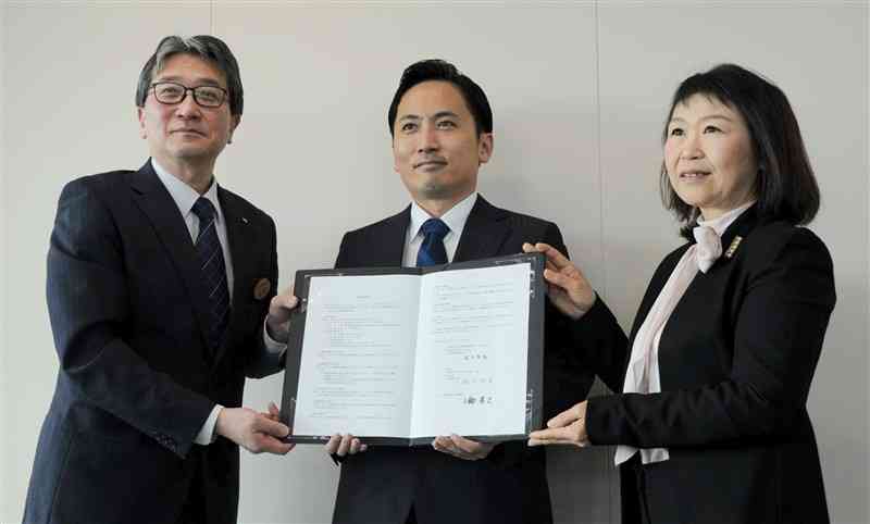 事業所新設に向け、熊本市と立地協定を結んだSBWorksの根本智勝社長（中央）ら＝25日、県庁