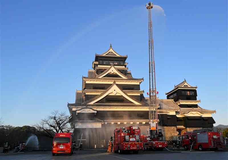 熊本城の総合消防訓練で、はしご車から放水する消防隊＝26日、熊本市中央区