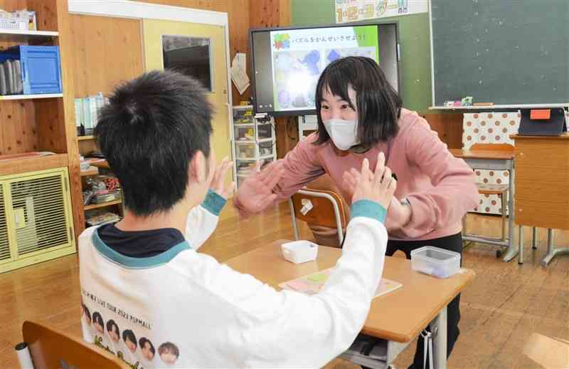 数学の授業で、問題を解いた生徒とハイタッチする奥村美空さん＝1月16日、熊本市中央区