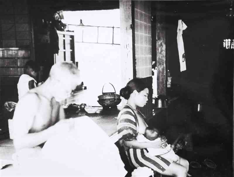 息子の妻が授乳している横で新聞を読んでいる神主＝1936年8月上旬