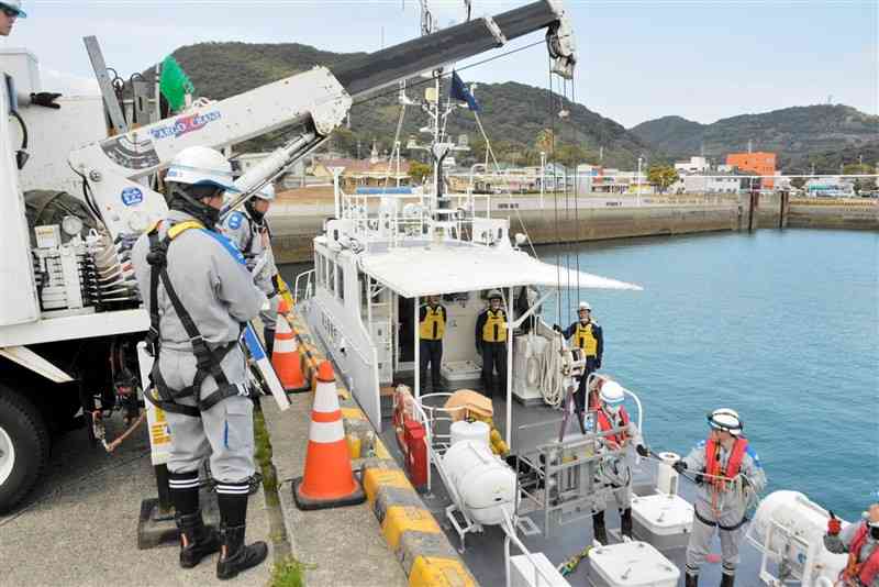 熊本海上保安部の巡視艇にクレーンで機材を積み込む九州電力送配電熊本支社の社員ら＝9日、宇城市