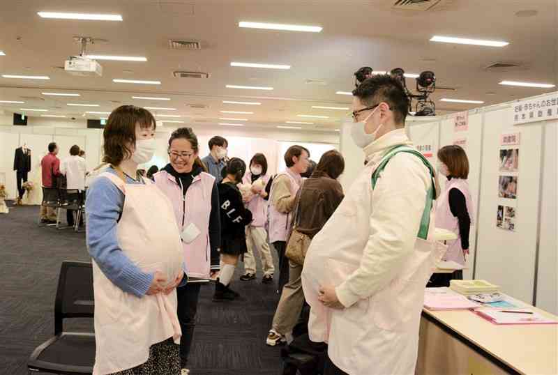 「ライフデザインフェス2024」で妊婦体験をするカップル＝12日、熊本市中央区