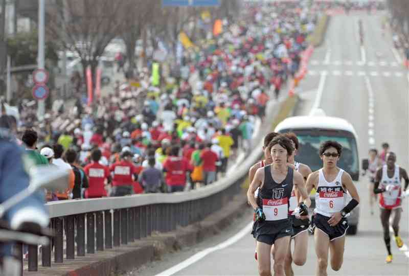 熊本西大橋を上る熊日30キロの選手たち。左側では橋を下るフルマラソンの行列が続いた＝2013年2月、熊本市南区（小野宏明）
