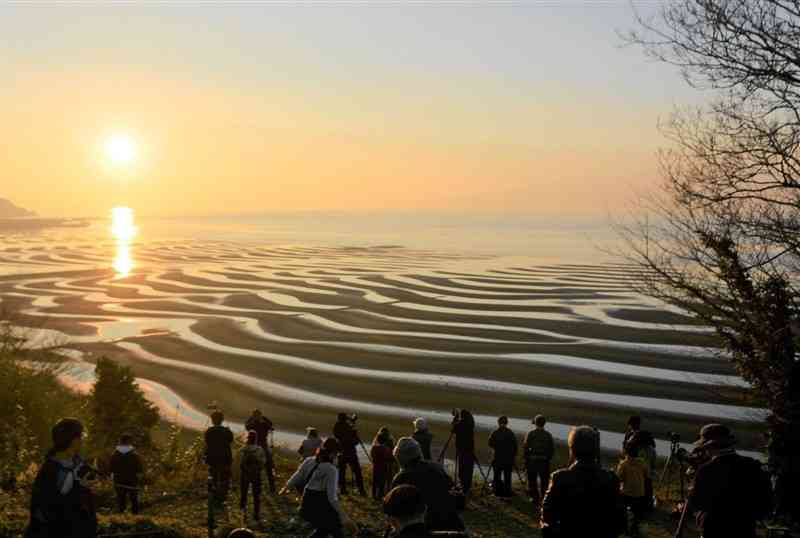 干潟に現れた砂紋と夕日によって幻想的な光景が広がる御輿来海岸＝12日、宇土市