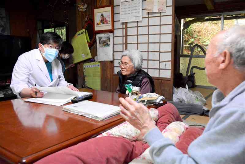 酒井さん宅で訪問診療に当たる河浦病院の中川和浩院長（左）＝14日午後、天草市河浦町