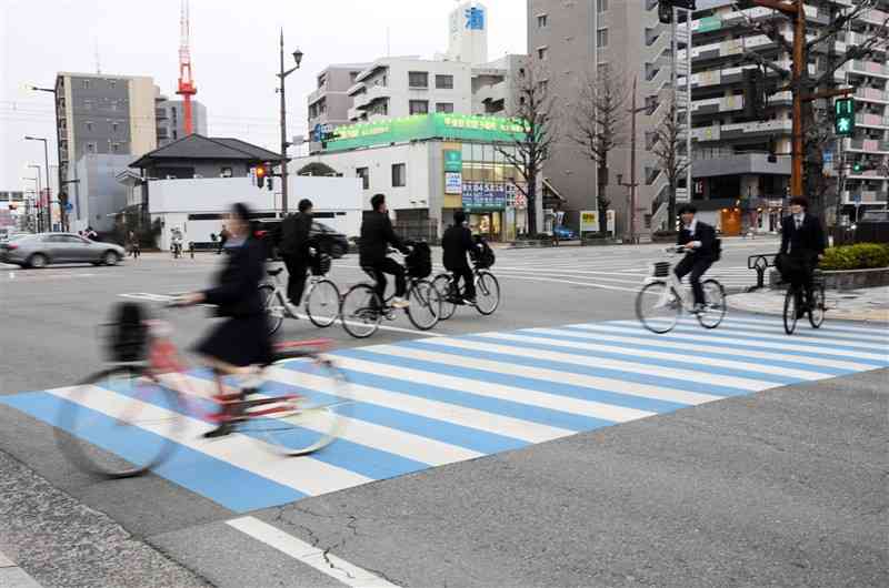 自転車で下校する高校生ら。ヘルメットを着用する生徒は見られなかった＝20日、熊本市中央区