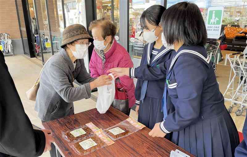 大根の栽培から加工まで携わった「寒漬」を販売する津奈木中の生徒ら＝26日、水俣市