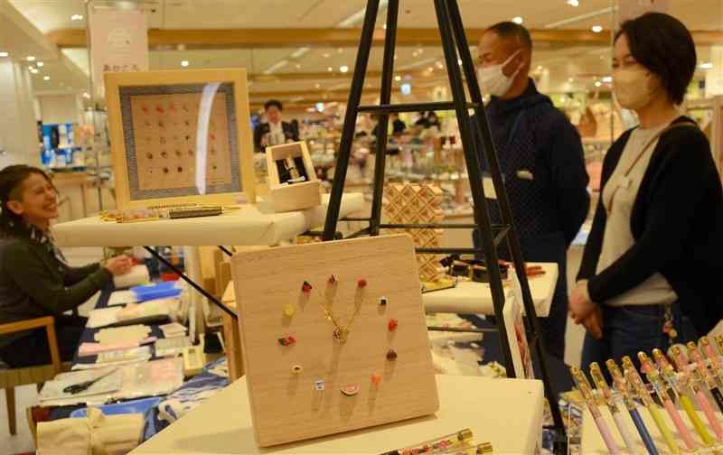 文字盤が熊本の特産品のミニチュアでできた桐時計などが並ぶ展示販売会＝28日、熊本市中央区