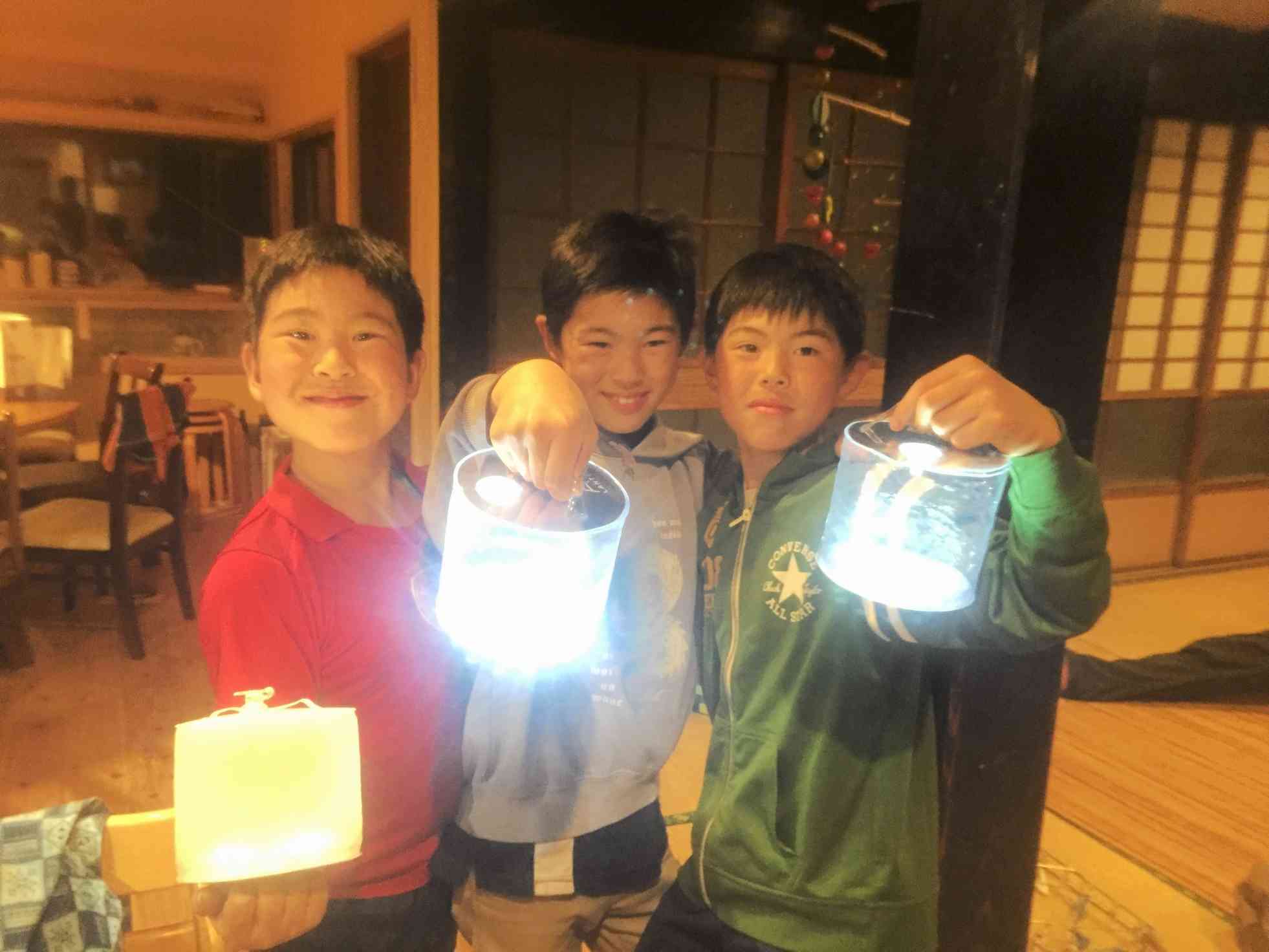 太陽光で充電できるソーラーランタンを持つ子供たち