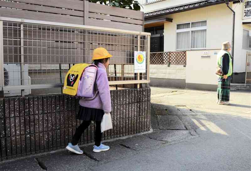 「こどもひなんの家」に登録している家の前を通って帰宅する女子児童（中央）＝2月13日、熊本市東区