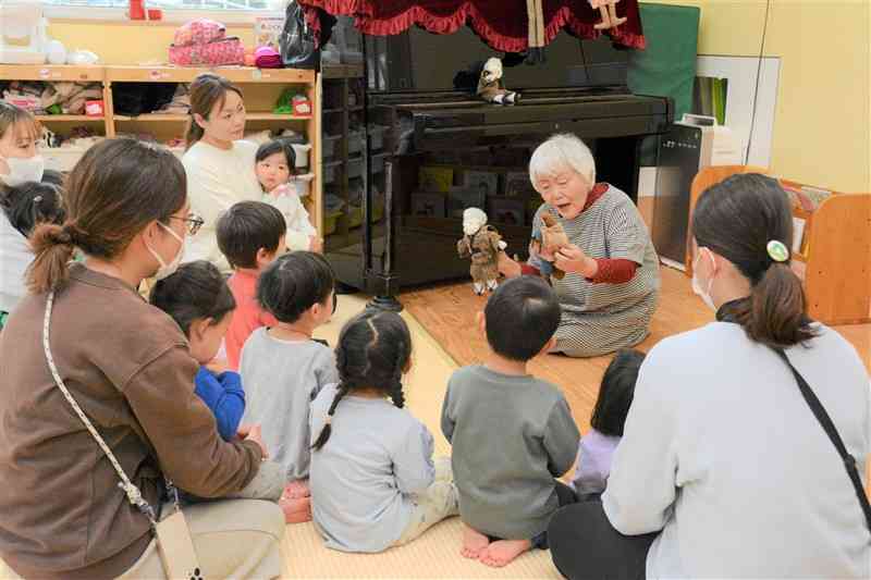 人形を使ったわらべうたで子どもたちの興味をひき付ける保育士の佐藤レイ子さん（右奥）＝2月29日、熊本市北区