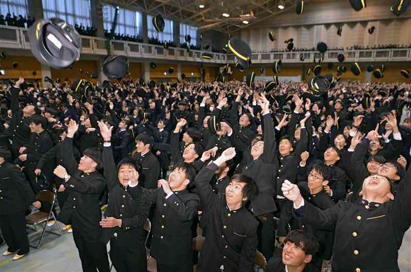 済々黌高の卒業式で、学生帽を投げ上げ喜び合う卒業生たち＝1日午後、熊本市中央区（小野宏明）
