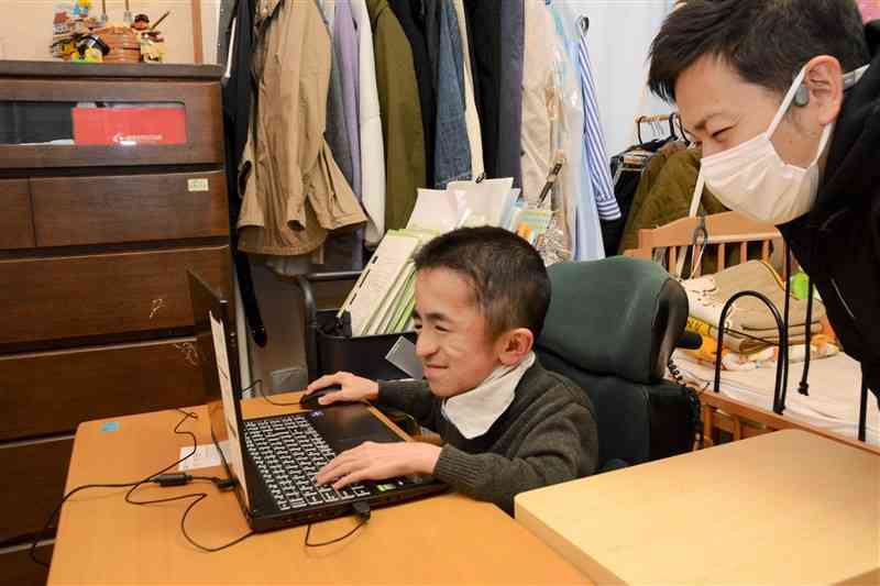 自宅でプログラミングを学ぶ木佐貫美貴さん（左）とハッピーブレインの池田竜太代表＝2023年12月、合志市