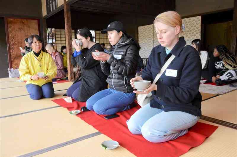 水前寺成趣園の古今伝授の間で、抹茶とお菓子を楽しむ外国人の参加者ら＝2日、熊本市中央区