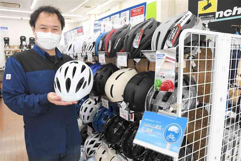 着用の努力義務を知らせる表示を掲げた「サイクルベースあさひ」くまなん店のヘルメット売り場＝8日、熊本市南区
