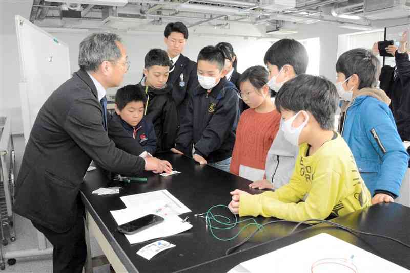 藤本邦昭教授（左）から半導体の仕組みの説明を受ける小中学生たち＝9日、益城町