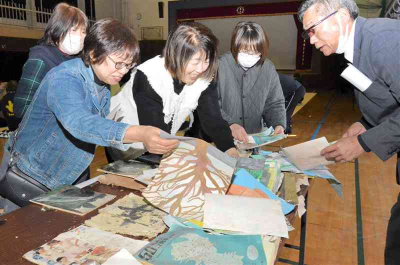 タイムカプセルに入れていた作文などを手に取り、懐かしむ旧下矢部東部小の卒業生ら＝10日、山都町