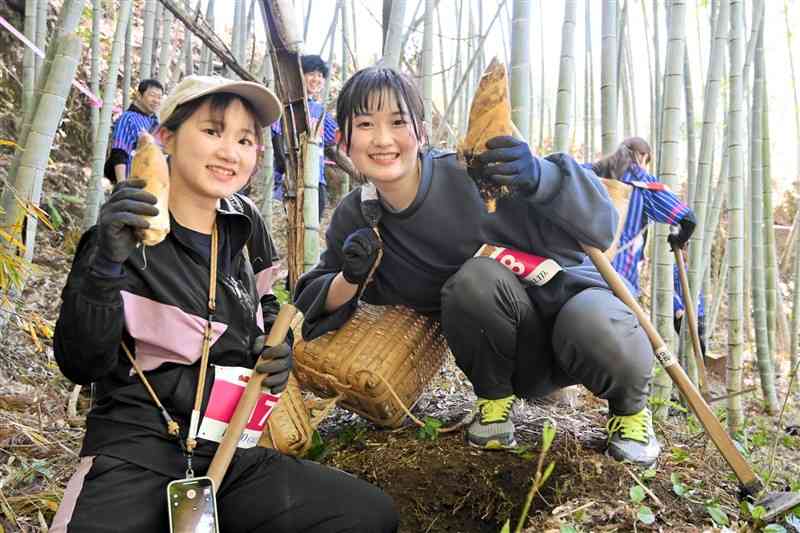 掘り出したタケノコを手に笑顔をみせる参加者＝16日、鞠智城一帯の竹林