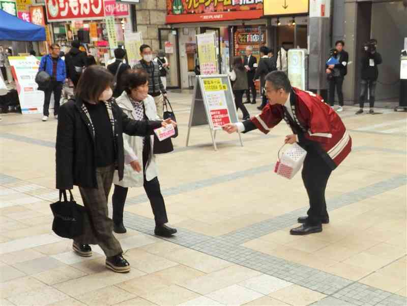 24日投開票の熊本県知事選への投票を通行人に呼びかける街頭活動の担当者（右）＝16日、熊本市中央区