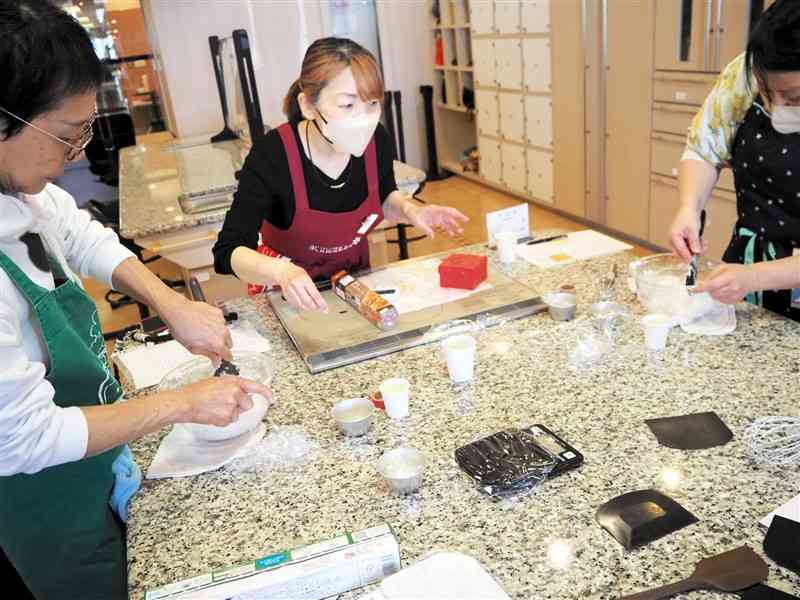 米粉パンの作り方を指導する川口朋子さん（中央）＝18日、熊本市中央区