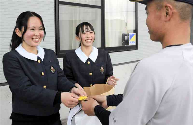 選手に手作りのお守りを手渡す可德ひば利さん（左）と中原愛美さん＝11日、合志市