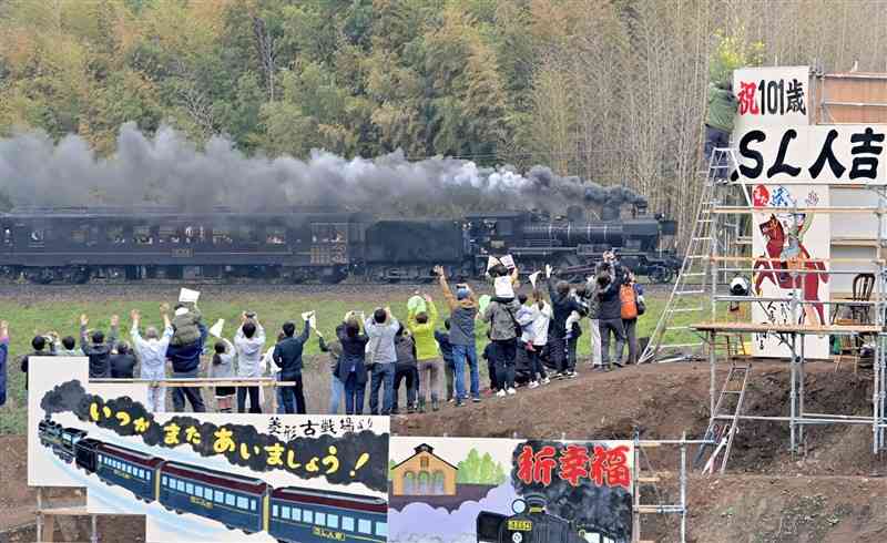 巨大看板と鉄道ファンらに見送られるSL人吉のラストラン＝23日午後5時20分ごろ、熊本市北区植木町（上杉勇太）