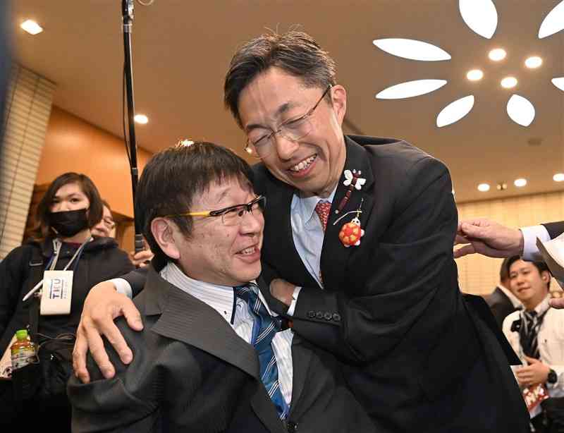 熊本県知事選で当選確実となり、車いすの支持者と笑顔で抱き合う木村敬さん（右）＝24日午後8時50分過ぎ、熊本市中央区のホテル熊本テルサ（石本智）