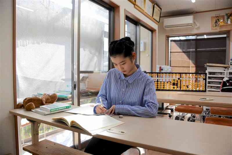 自宅のそろばん教室で、韓国語の勉強に励む人吉高2年の安藤マヤさん＝16日、人吉市