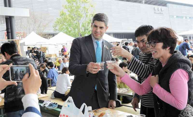 来場者と熊本県産酒で乾杯するジョージアの駐日大使ティムラズ・レジャバさん＝30日、熊本市西区