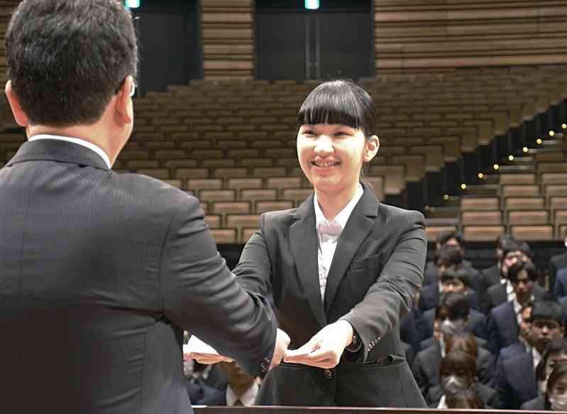 大西一史熊本市長（左）から辞令を笑顔で受け取る新規採用職員の佐藤舞奈さん＝1日、熊本市中央区