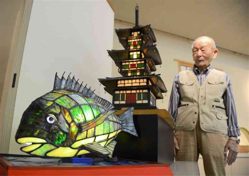 クロダイ（手前）や薬師寺三重塔（中央）を題材にしたステンドグラス作品を並べた岩下圭介さん＝3日、熊本市南区