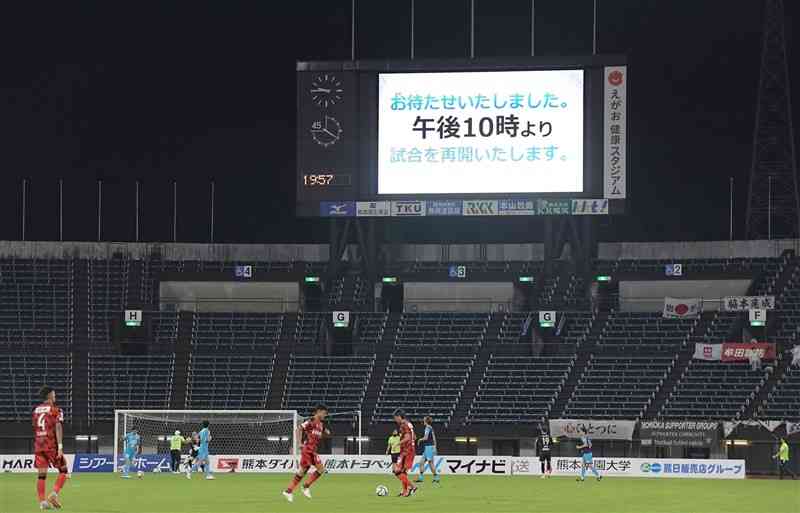 後半途中の雷雨で一時中断し、午後10時の再開に備えるロアッソ熊本の選手たち＝2021年7月、えがお健康スタジアム（小野宏明）