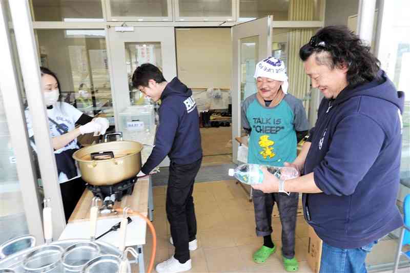 石川県志賀町の富来防災センターの避難所で住民と談笑しながらラーメンの炊き出しをするバルビーの中村聖悟さん（右端）ら＝6日午後