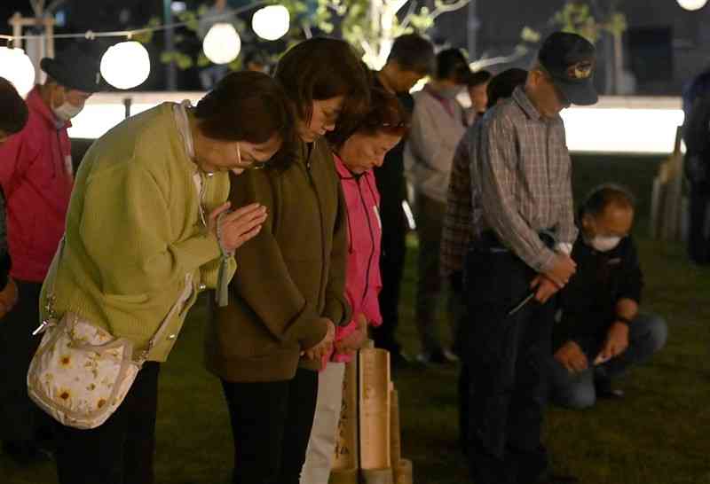 熊本地震の前震が発生した時刻に合わせ、益城町震災記念公園で黙とうする住民たち＝14日午後9時25分ごろ、同町（石本智）