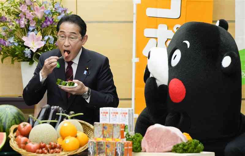 JAグループ熊本から贈呈されたスイカを試食する岸田首相。右は官邸を初訪問したくまモン＝15日、首相官邸