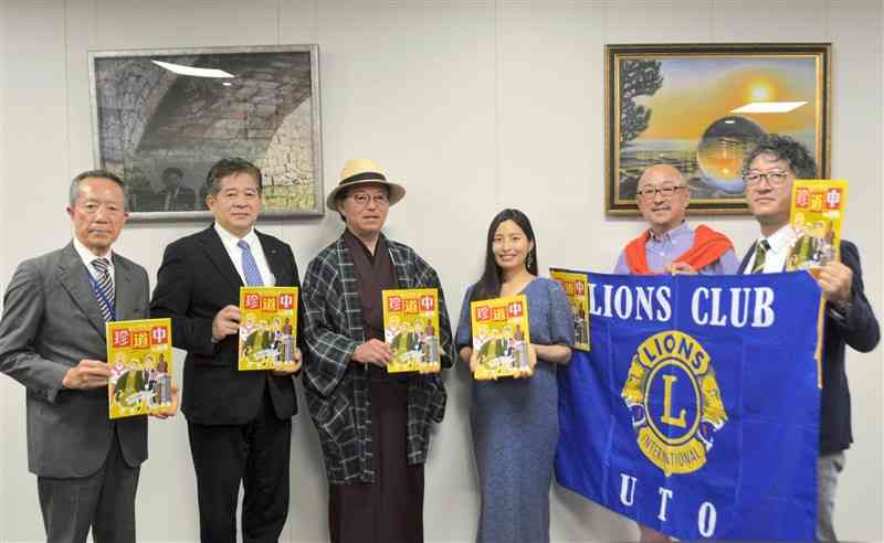 漫画家の内田麻美さん（左から4人目）が描いた湯徳章を紹介する漫画を元松茂樹市長（同2人目）らに贈呈したライオンズクラブのメンバー＝18日、宇土市