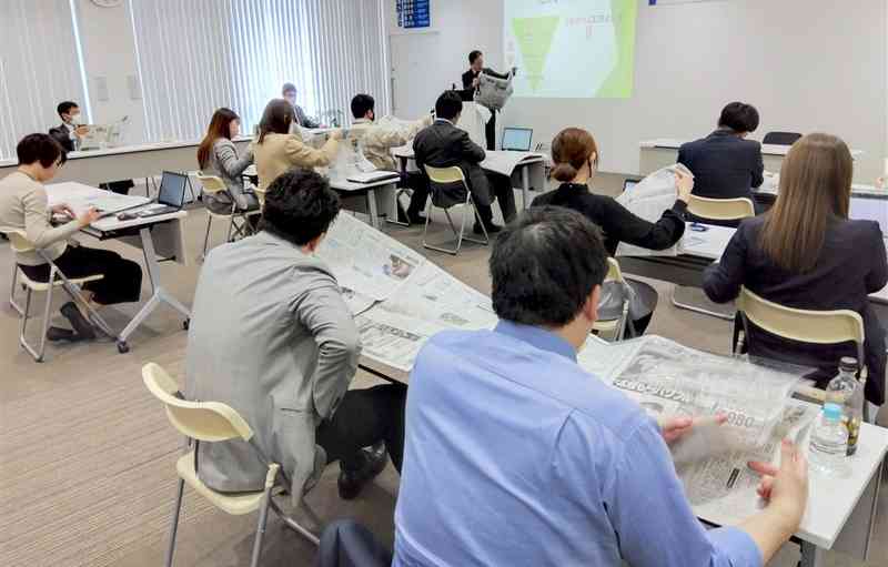 熊日を手に取り、新聞の読み方や活用法の説明を受けるNIB講座の受講者＝22日、熊本市南区