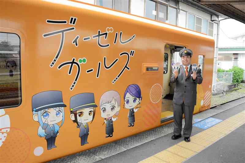 肥薩おれんじ鉄道のラッピング列車「ディーゼルガールズ号」と運転士の中居靖幸さん＝23日、八代市