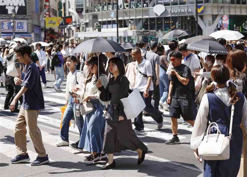 東京・渋谷のスクランブル交差点を日傘を差して歩く人たち＝28日午後