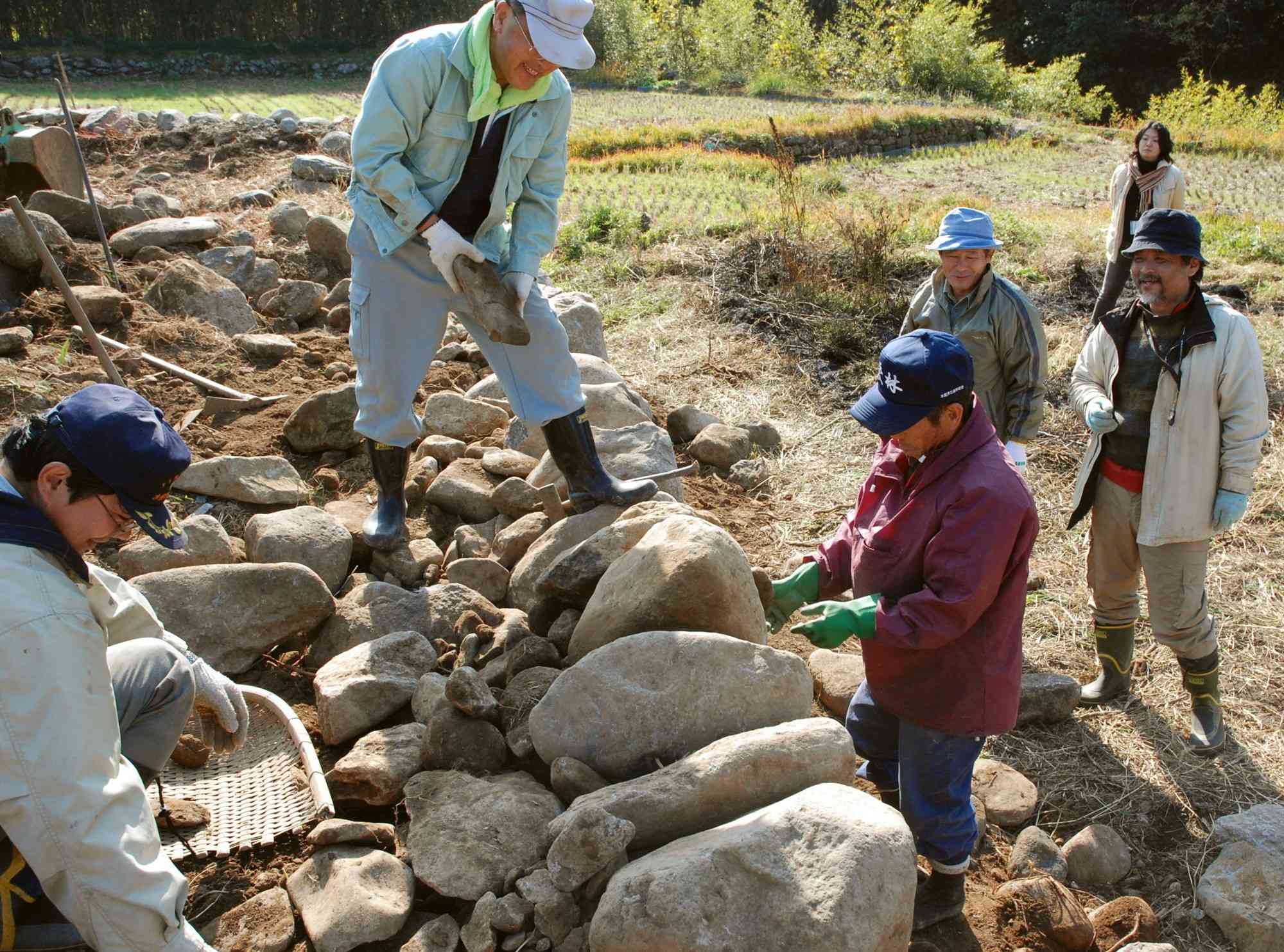 「石垣積み教室」で、指導を受けながら石を積んでいく参加者＝2007年12月、水俣市久木野