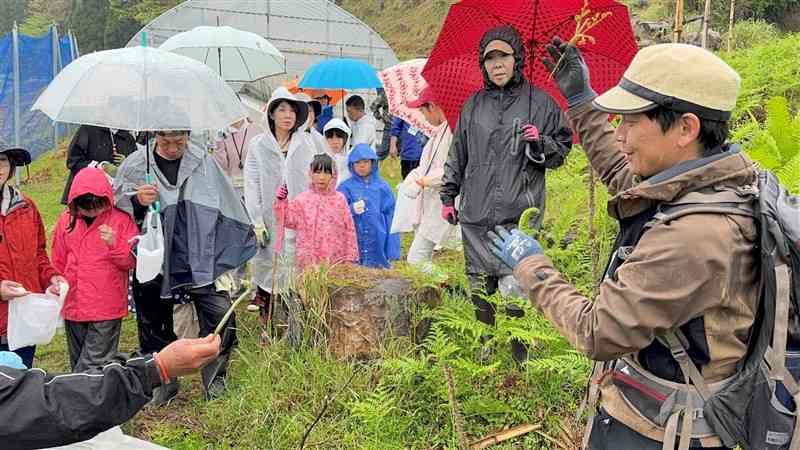 山菜採りのコツを伝授するガイドの早野慎哉さん（右）＝4月21日、高森町