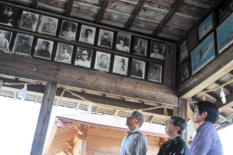 拝殿の遺影を見上げる左から古江研也さん、星子都さん、濱武春美さん。遺影は下段の左端が永田博信さん、左から5人目が城下孝農夫さん＝4月16日、山鹿市