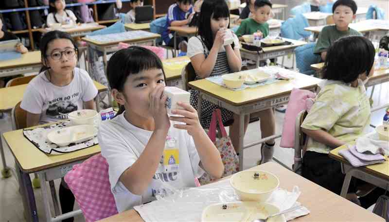 用心しながら、牛乳パックに直接口を付けて飲む黒髪小の児童＝18日、熊本市中央区