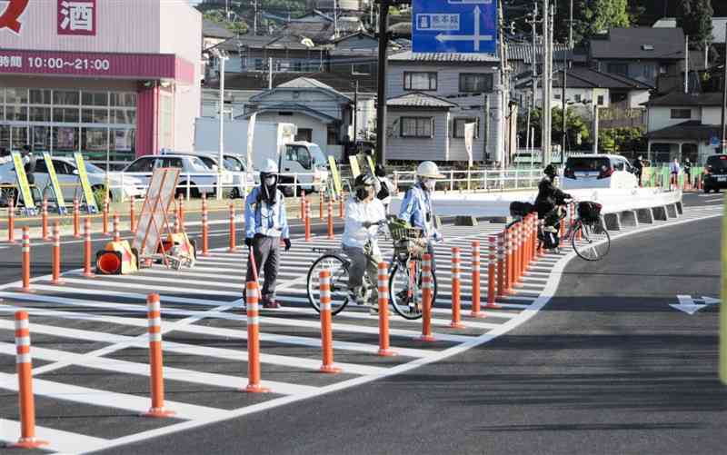 車が行き交う中、都市計画道路「野口島崎線」を横断する人たち＝4月25日、熊本市西区