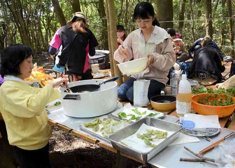 森で採った野草をてんぷらにする野草アドバイザーの山本愛子さん（右）＝4日、天草市