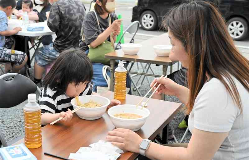 提供されたラーメンを味わう親子＝5日、山鹿市