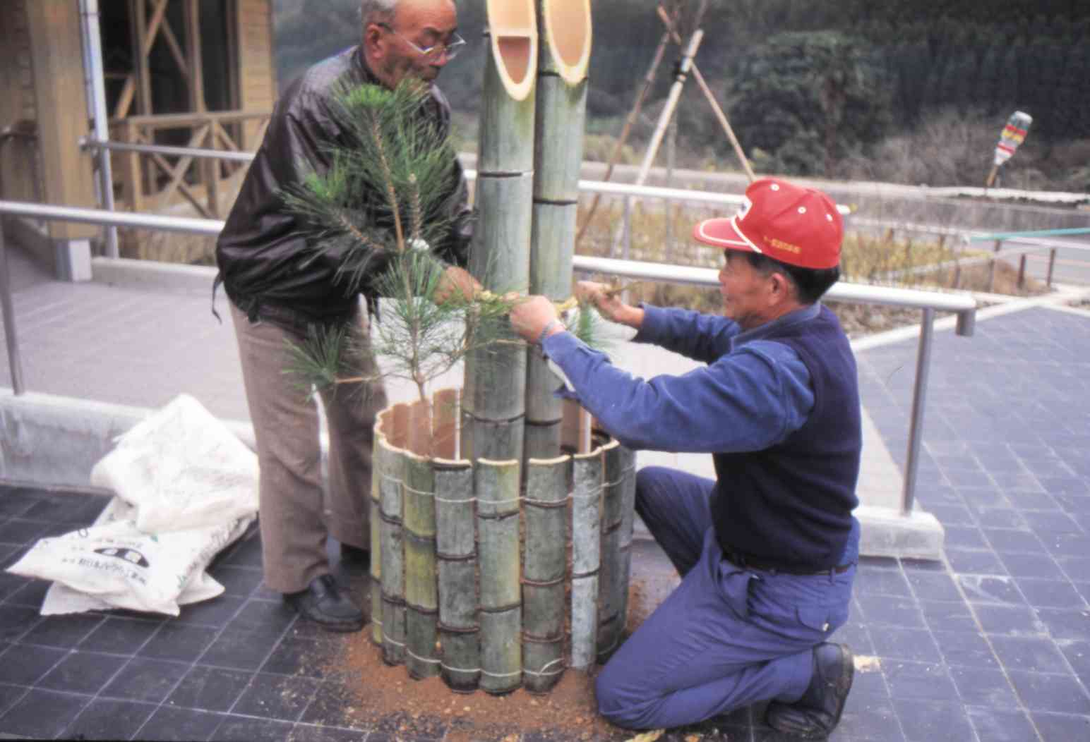 愛林館で初のお正月を前に、門松を準備する地域住民。左は管理人の松下義春さん＝1994年12月