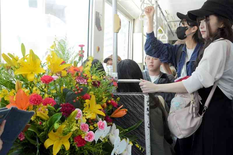母の日に合わせてカーネーションなどが飾られた市電の車内＝10日、熊本市